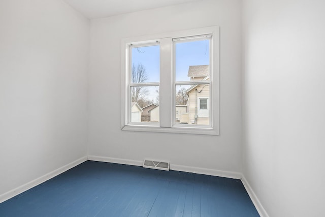 unfurnished room featuring visible vents, dark wood finished floors, and baseboards