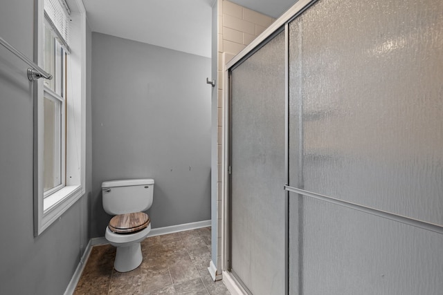 full bathroom featuring a shower stall, toilet, and baseboards