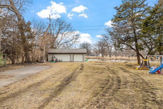 view of yard with an outbuilding, a playground, and a detached garage