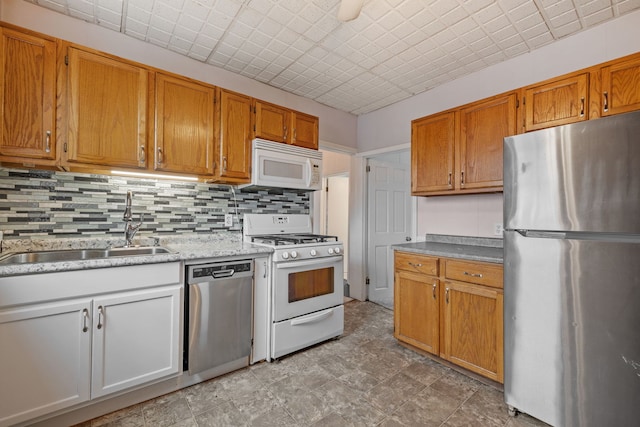 kitchen featuring appliances with stainless steel finishes, brown cabinetry, a sink, and backsplash