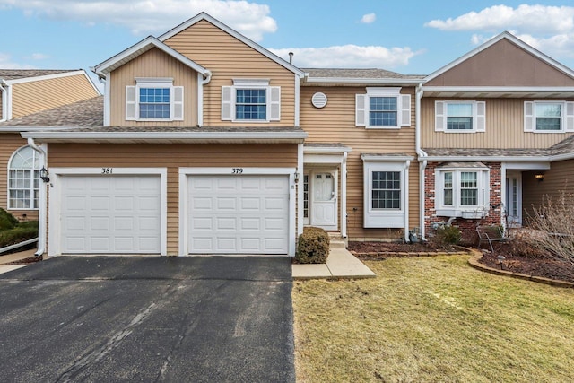 townhome / multi-family property with driveway, an attached garage, a front yard, and roof with shingles