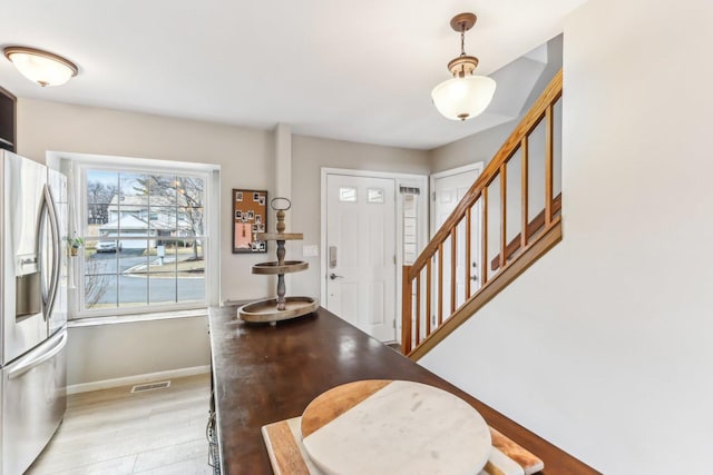 foyer featuring stairway, baseboards, and visible vents