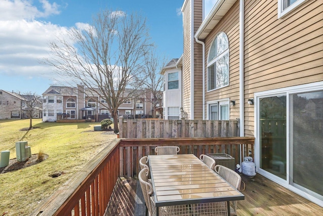 deck with outdoor dining area, a residential view, and a lawn