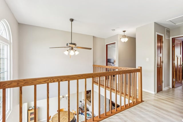 hallway featuring an upstairs landing, visible vents, light wood finished floors, and baseboards