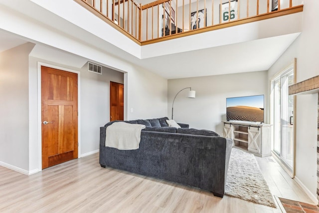 living area featuring visible vents, baseboards, a high ceiling, and wood finished floors