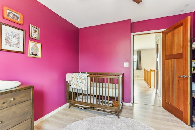 bedroom with a crib, baseboards, and wood finished floors