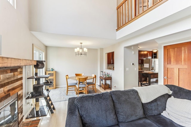 living room with an inviting chandelier, a high ceiling, wood finished floors, and baseboards