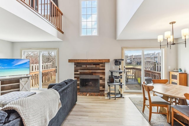 living room featuring a fireplace, wood finished floors, a notable chandelier, and a healthy amount of sunlight