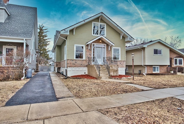 bungalow-style house with aphalt driveway and brick siding