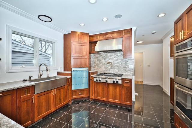 kitchen featuring a sink, tasteful backsplash, recessed lighting, stainless steel appliances, and wall chimney range hood