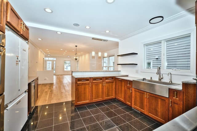 kitchen featuring brown cabinets, ornamental molding, a sink, recessed lighting, and a peninsula