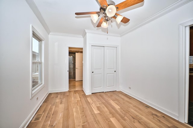 unfurnished bedroom with light wood-type flooring, visible vents, baseboards, and crown molding