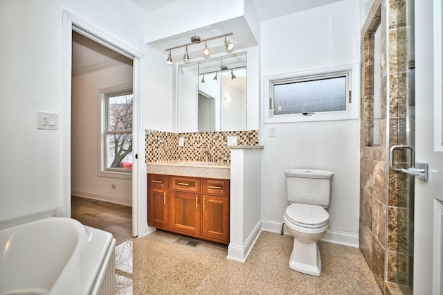 bathroom featuring tasteful backsplash, a washtub, toilet, and baseboards