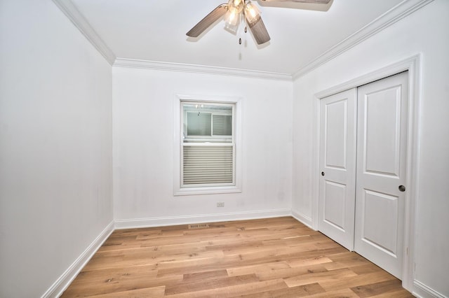 empty room with baseboards, light wood finished floors, a ceiling fan, and crown molding