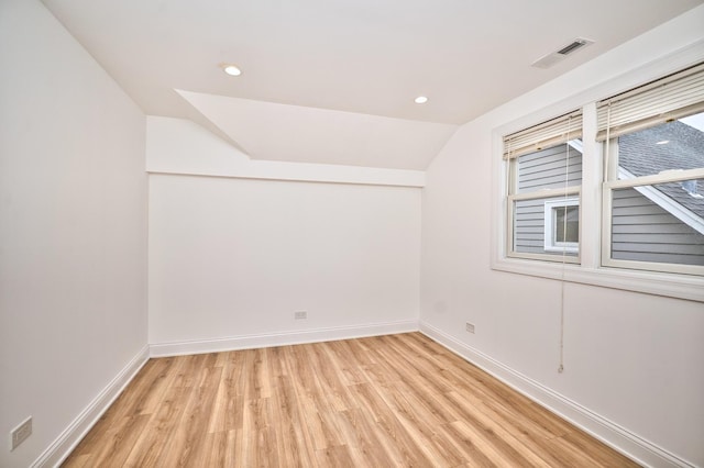 unfurnished room with baseboards, visible vents, recessed lighting, vaulted ceiling, and light wood-type flooring