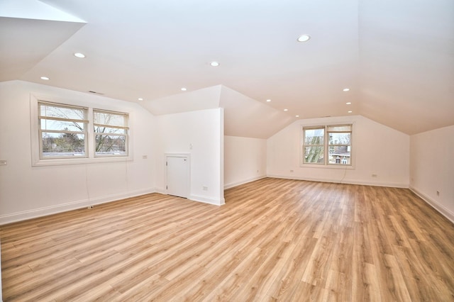 additional living space featuring baseboards, lofted ceiling, and light wood-style flooring