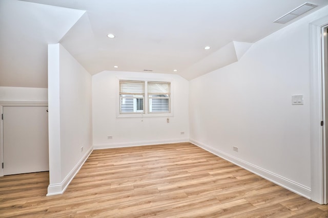 unfurnished room with visible vents, baseboards, light wood-style flooring, and vaulted ceiling