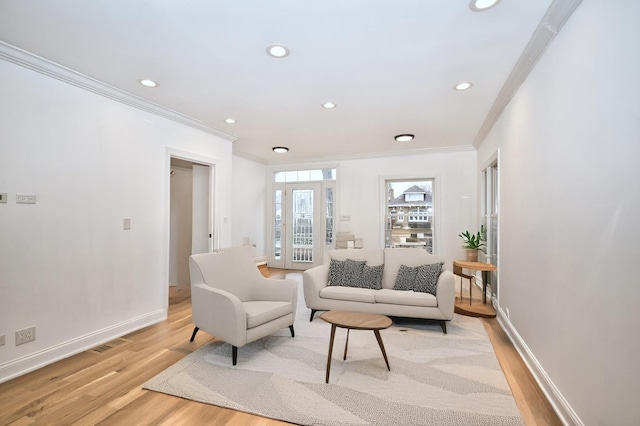 living room with light wood finished floors, visible vents, crown molding, and baseboards