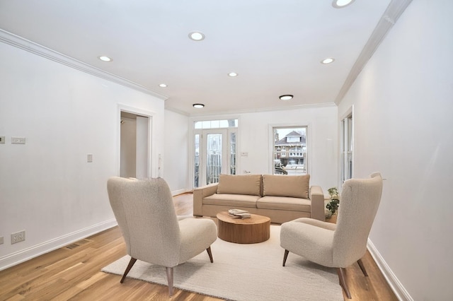 living room featuring visible vents, baseboards, light wood-style flooring, and ornamental molding