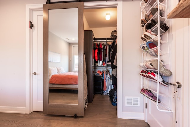 spacious closet with dark wood-style flooring, visible vents, and a barn door