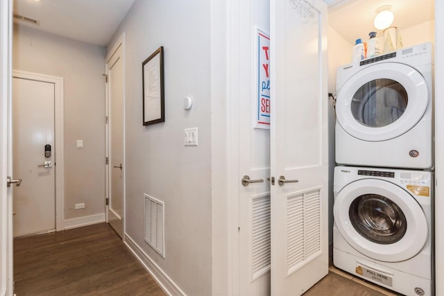 clothes washing area with stacked washer and dryer, laundry area, visible vents, and dark wood-type flooring