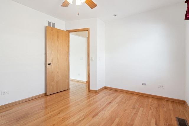 empty room with light wood-style floors, visible vents, baseboards, and a ceiling fan