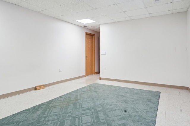 empty room featuring a drop ceiling and baseboards