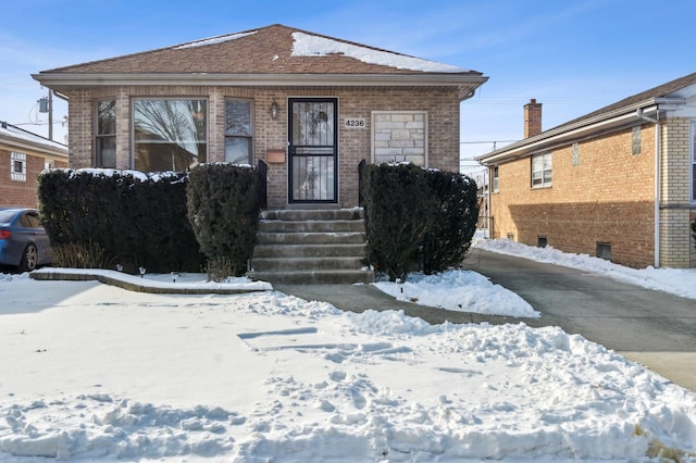 bungalow-style house with entry steps and brick siding