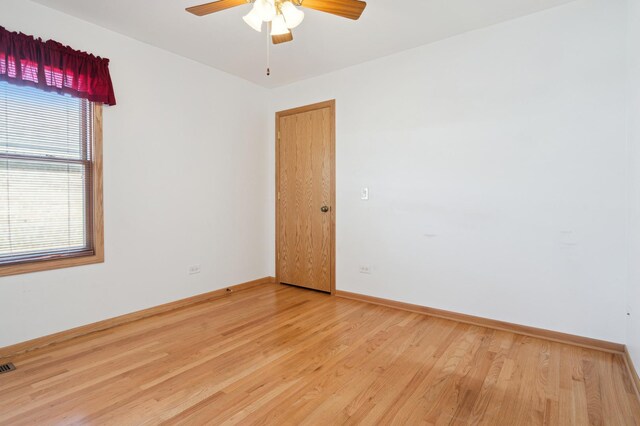 spare room with a ceiling fan, visible vents, baseboards, and wood finished floors