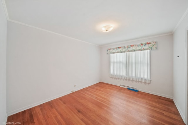 empty room featuring ornamental molding, wood finished floors, and baseboards