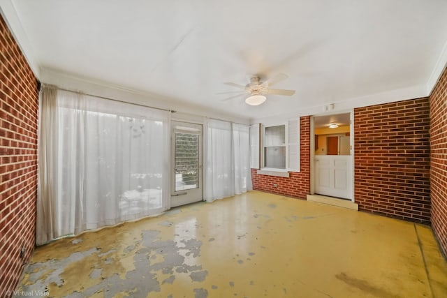 spare room with unfinished concrete flooring, brick wall, and ceiling fan