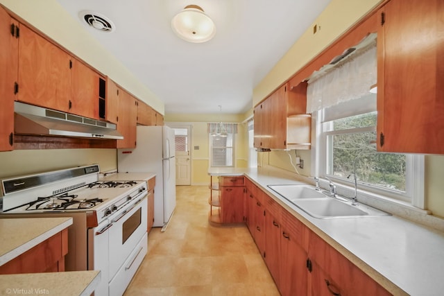 kitchen featuring visible vents, light countertops, a sink, white appliances, and under cabinet range hood