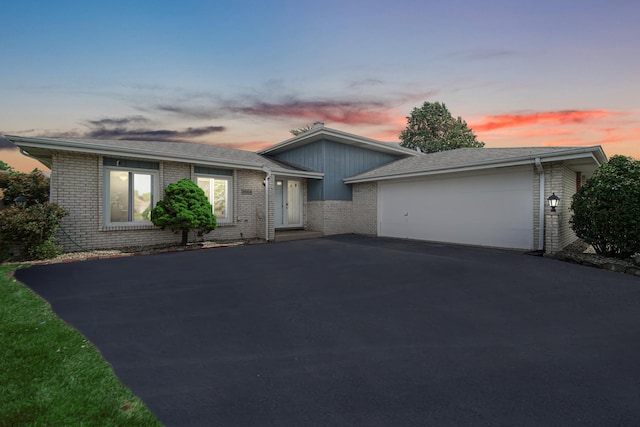 view of front of property with aphalt driveway, brick siding, and an attached garage