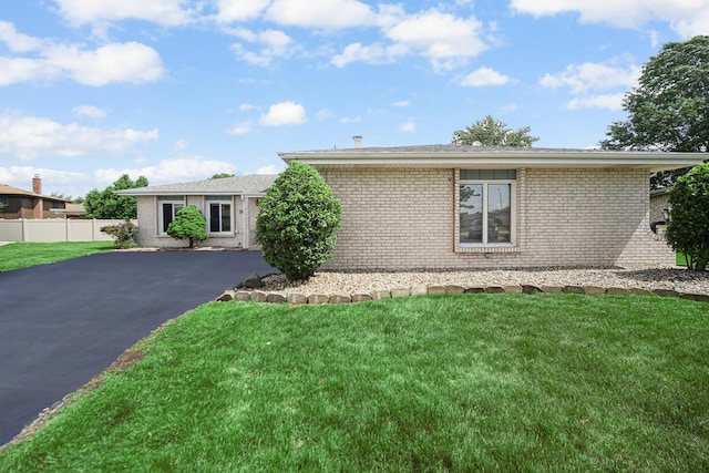 view of front facade with driveway, a front yard, fence, and brick siding