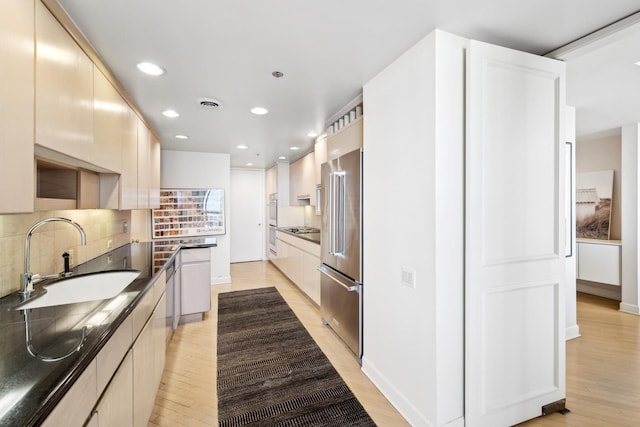 kitchen featuring dark countertops, a sink, visible vents, and high end fridge