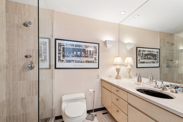 full bathroom with toilet, tiled shower, and vanity