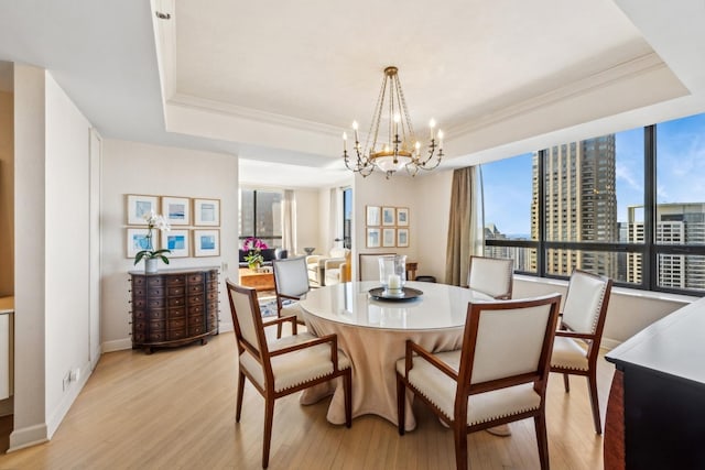 dining room featuring plenty of natural light, light wood-style flooring, a view of city, and a raised ceiling