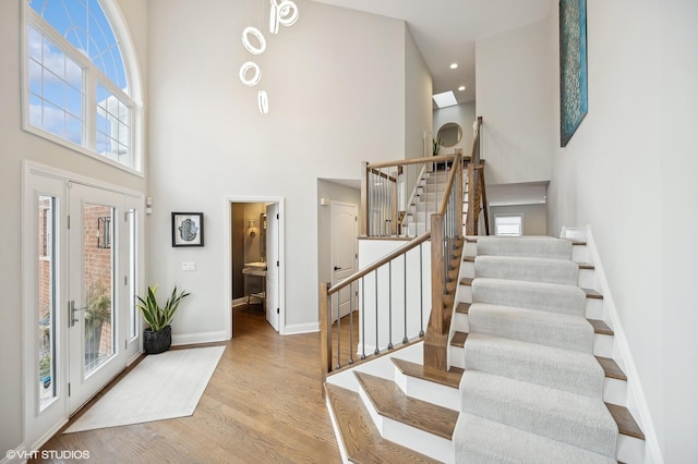 entrance foyer featuring stairs, baseboards, a high ceiling, and wood finished floors