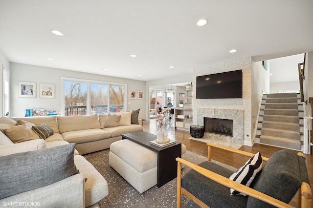living room with stairway, wood finished floors, a high end fireplace, and recessed lighting