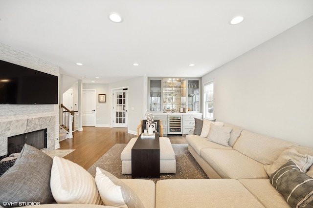 living room with beverage cooler, wood finished floors, a high end fireplace, and recessed lighting