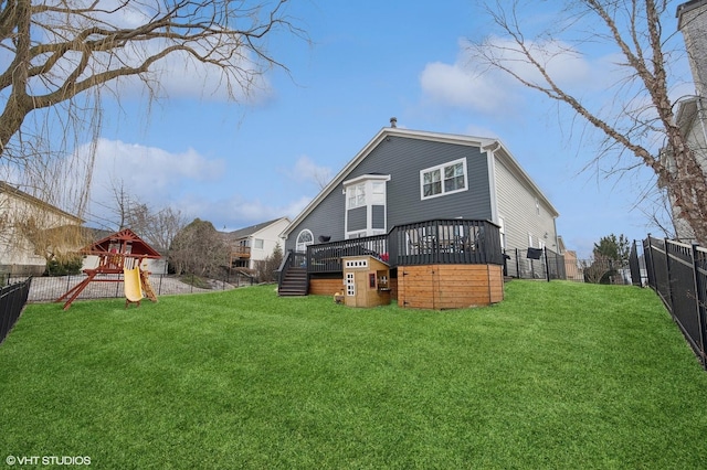 back of property with a fenced backyard, a yard, and a playground