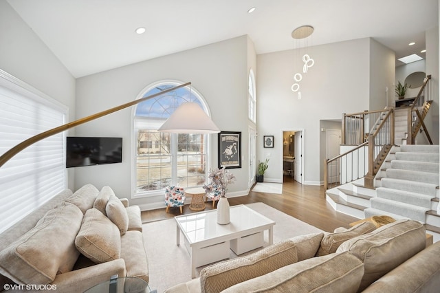 living room featuring stairs, baseboards, wood finished floors, and recessed lighting