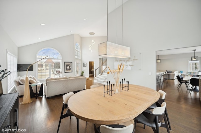 dining space with stairs, high vaulted ceiling, dark wood finished floors, and a wealth of natural light