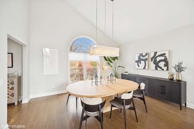 dining space featuring baseboards, high vaulted ceiling, and wood finished floors