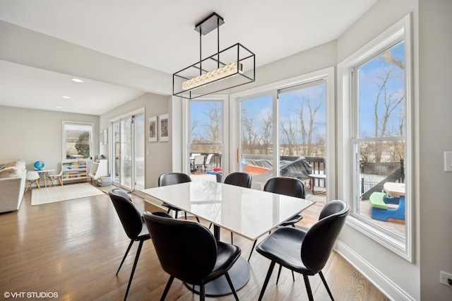 dining space featuring a notable chandelier, baseboards, wood finished floors, and recessed lighting