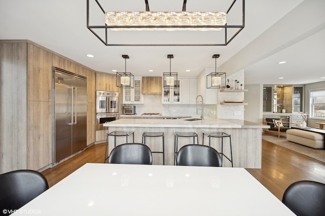 kitchen featuring a breakfast bar, a sink, light countertops, appliances with stainless steel finishes, and decorative backsplash