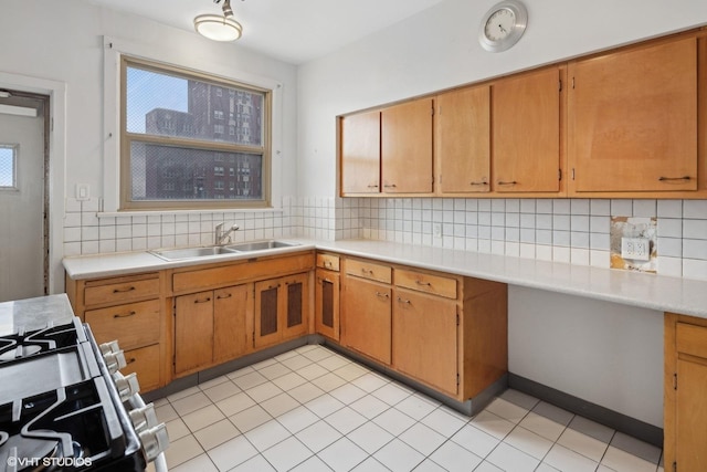 kitchen with light tile patterned flooring, sink, gas range, and tasteful backsplash