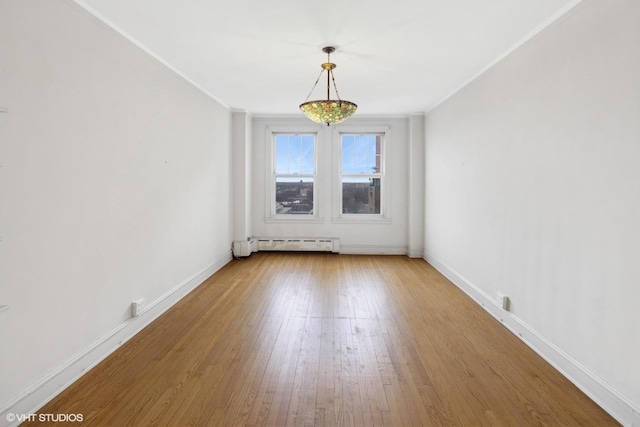 unfurnished room with hardwood / wood-style floors, baseboard heating, and ornamental molding