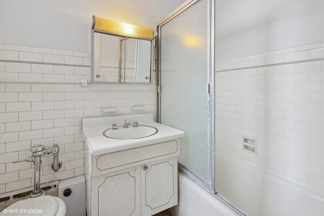 full bathroom featuring toilet, tile walls, combined bath / shower with glass door, and vanity