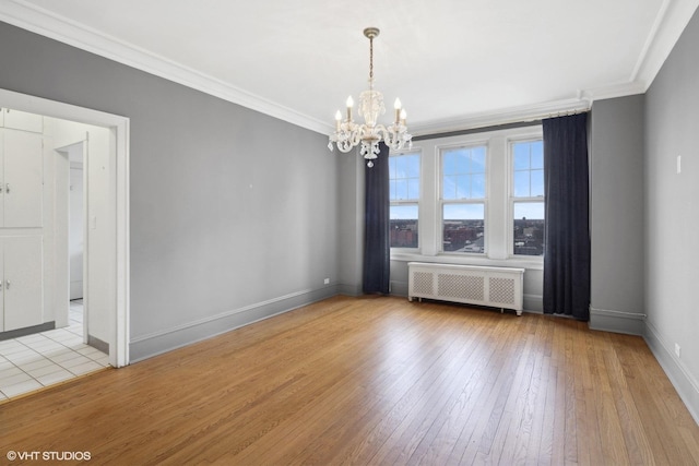 spare room featuring light hardwood / wood-style flooring, a chandelier, radiator, and ornamental molding